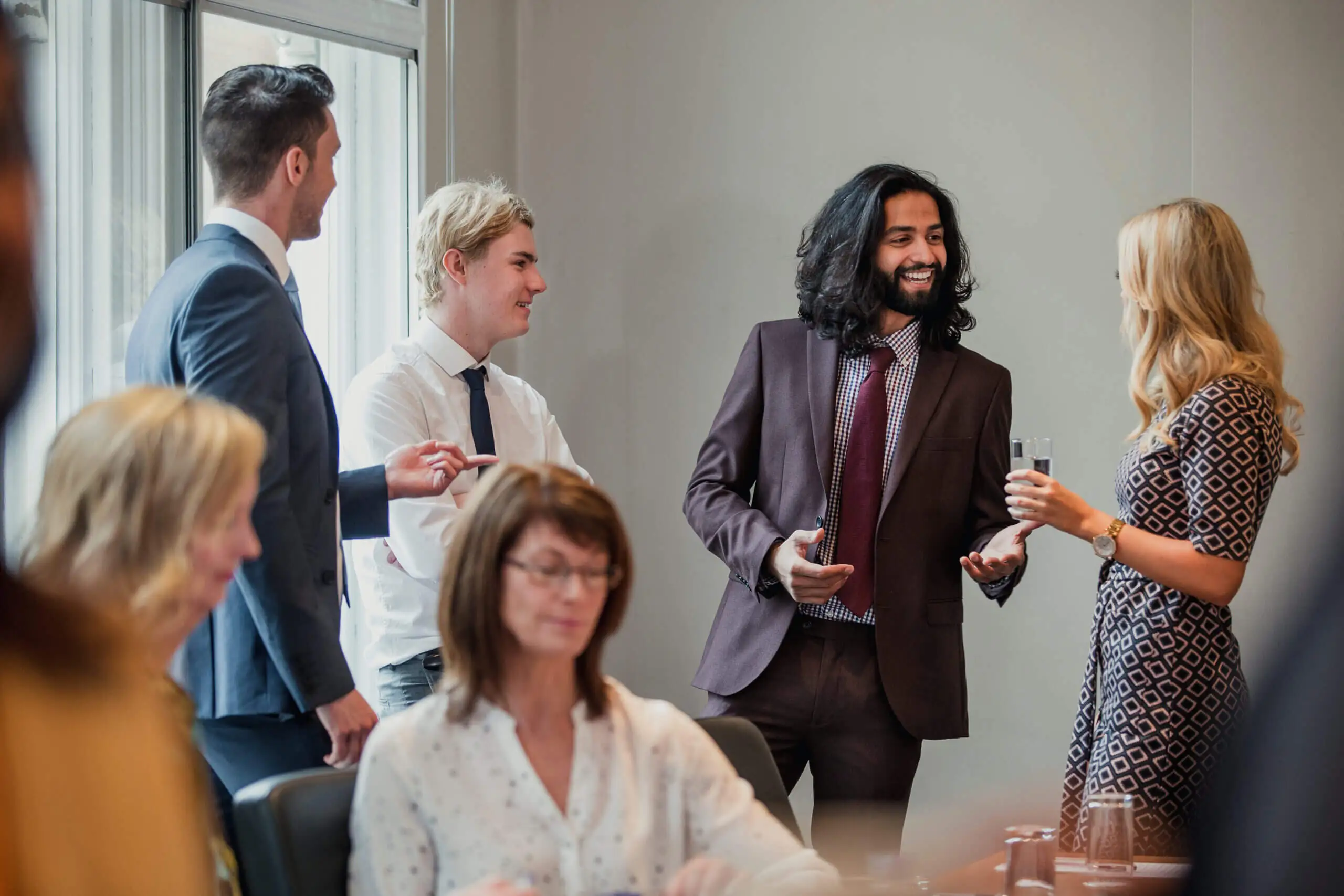 Businessmen and women meetin and greeting each other in office setting.