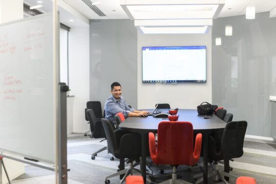 A man sitting at a board table in a conerence room smiles at the camera.