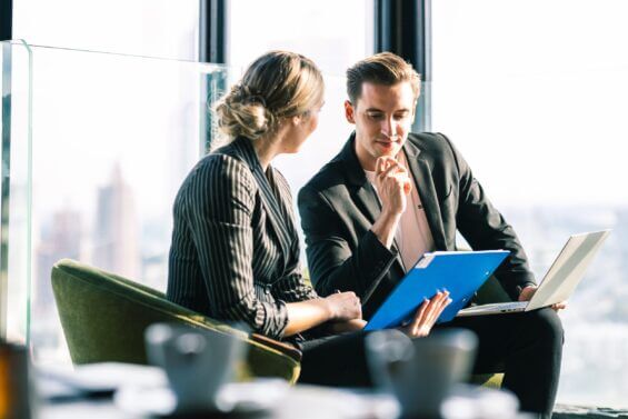 Two business people have a discussion on a rooftop.