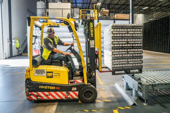 A man operates a piece of machinery in a warehouse distribution center.